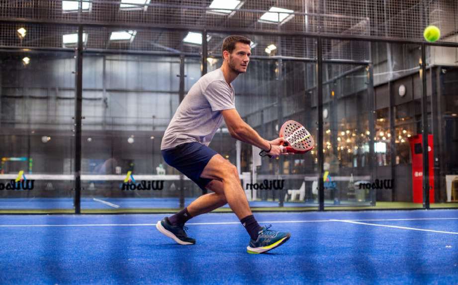 Joueur de padel en action sur un court bleu